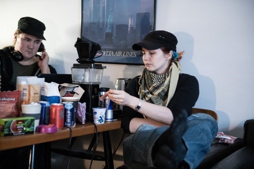 photo of people in black working near a table with snacks, with one listening to headphones