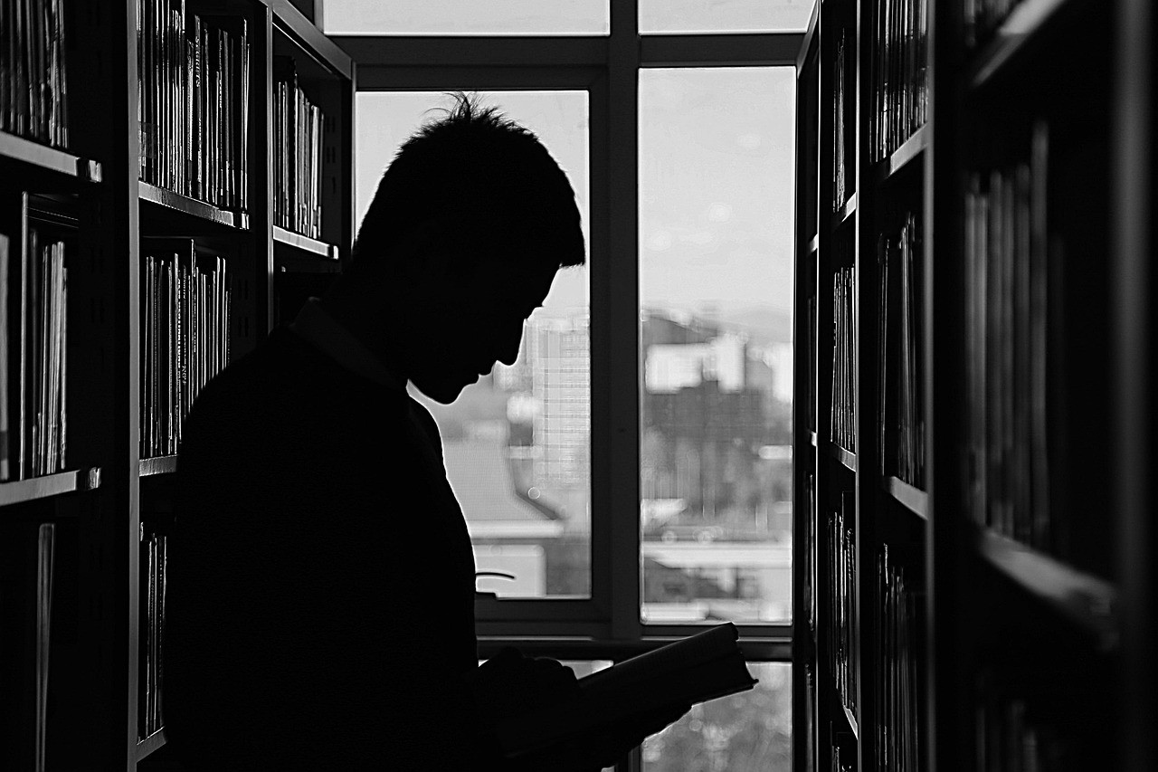 silhouette d'homme au millieu d'étagères de livres