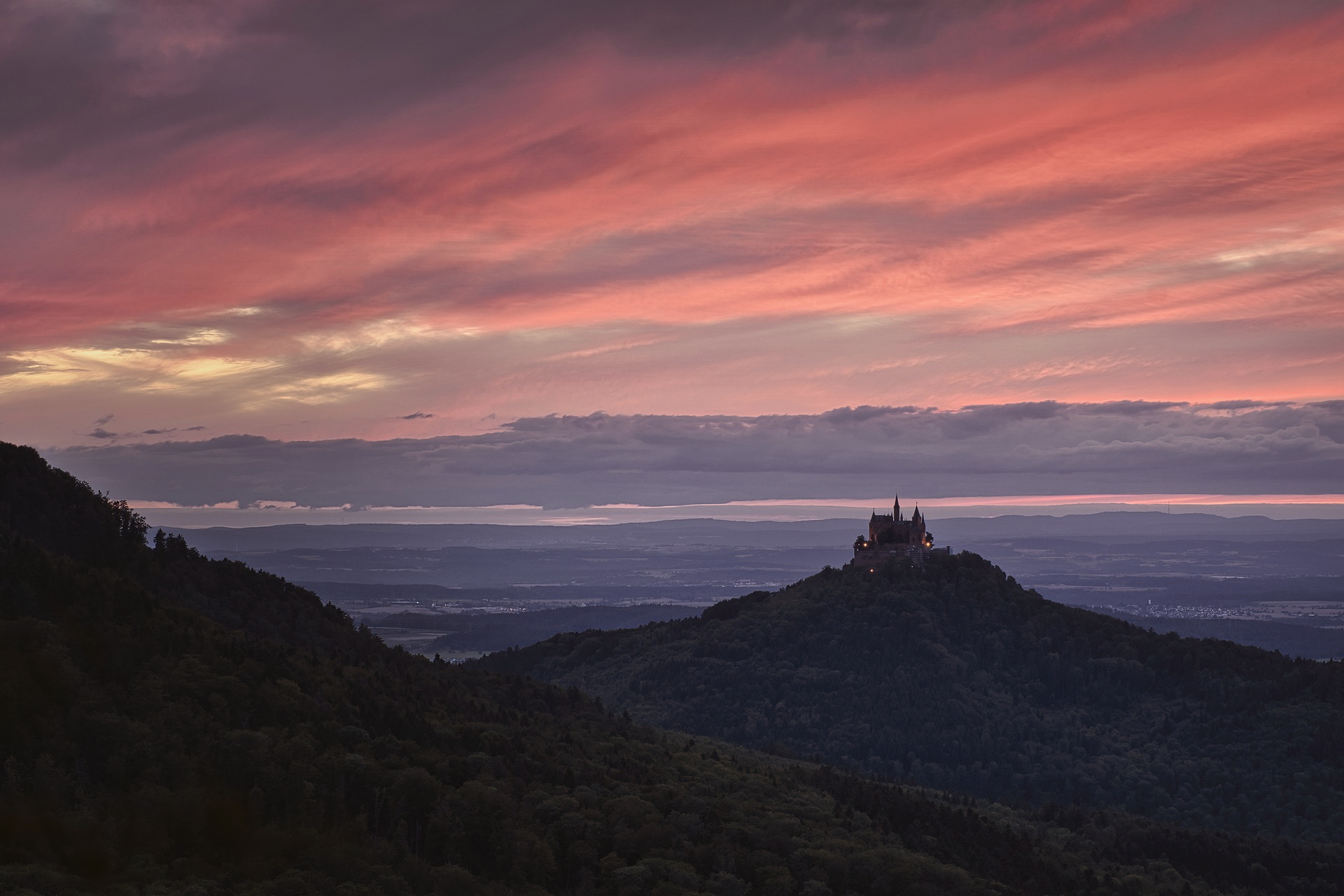 photo de chateau sur une colline, au crépuscule, devant une plaine