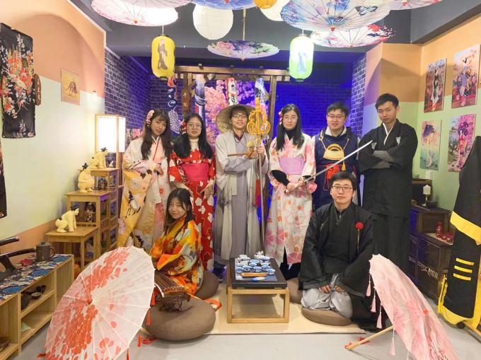 Un groupe de 4 jeunes joueuses et 4 jeunes joueurs prennent la pose avec des épées, des chapeaux de moine et des parasols.