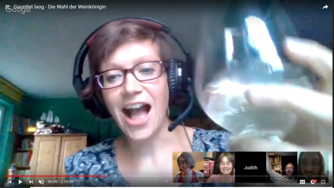 Image montrant une des joueuses chez elle en train de lever un verre de vin blanc vers la caméra, probablement en train de faire un discours.