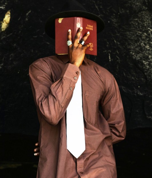 Homme en costume se cachant le visage derrière un missel